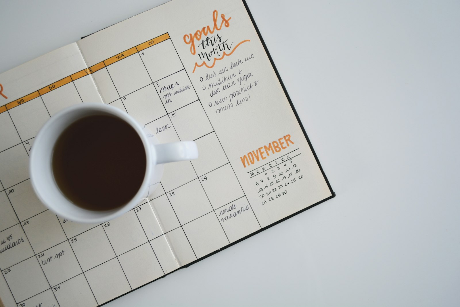 A paper planner with handwritten goals beside a cup of coffee